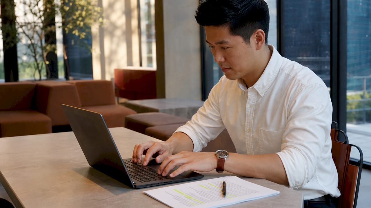 Close-up hands typing on laptop with framework checklist