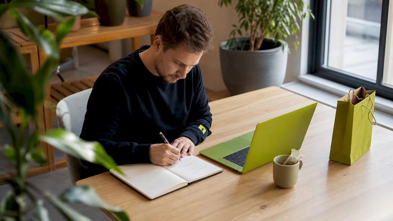 De contentstrateeg zit achter zijn laptop en maakt notities terwijl hij typt.