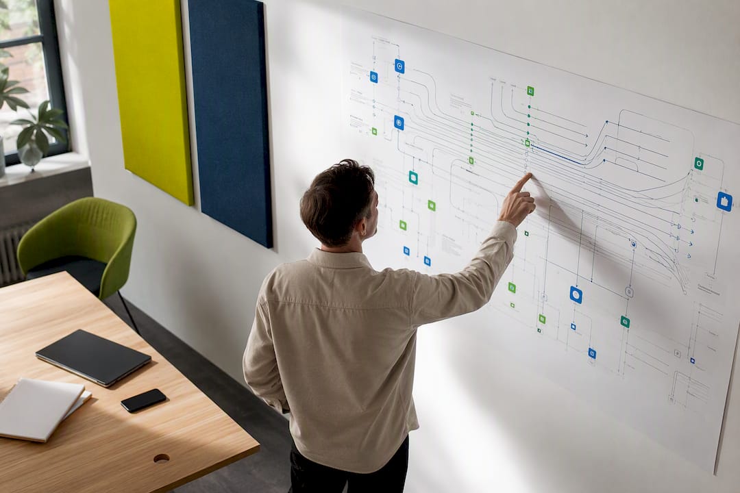Een hand wijst naar een schema van AI-data-architectuur op de muur.
