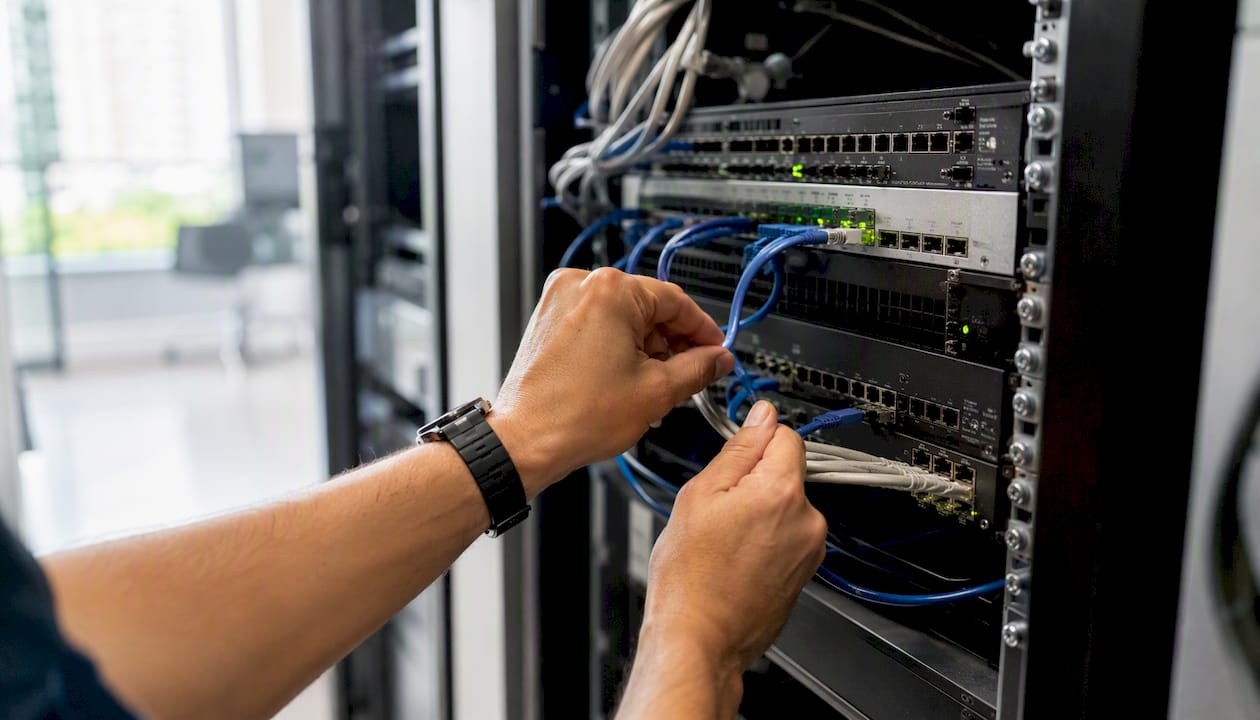 Handen die serverkabels aanpassen in een IT-rack