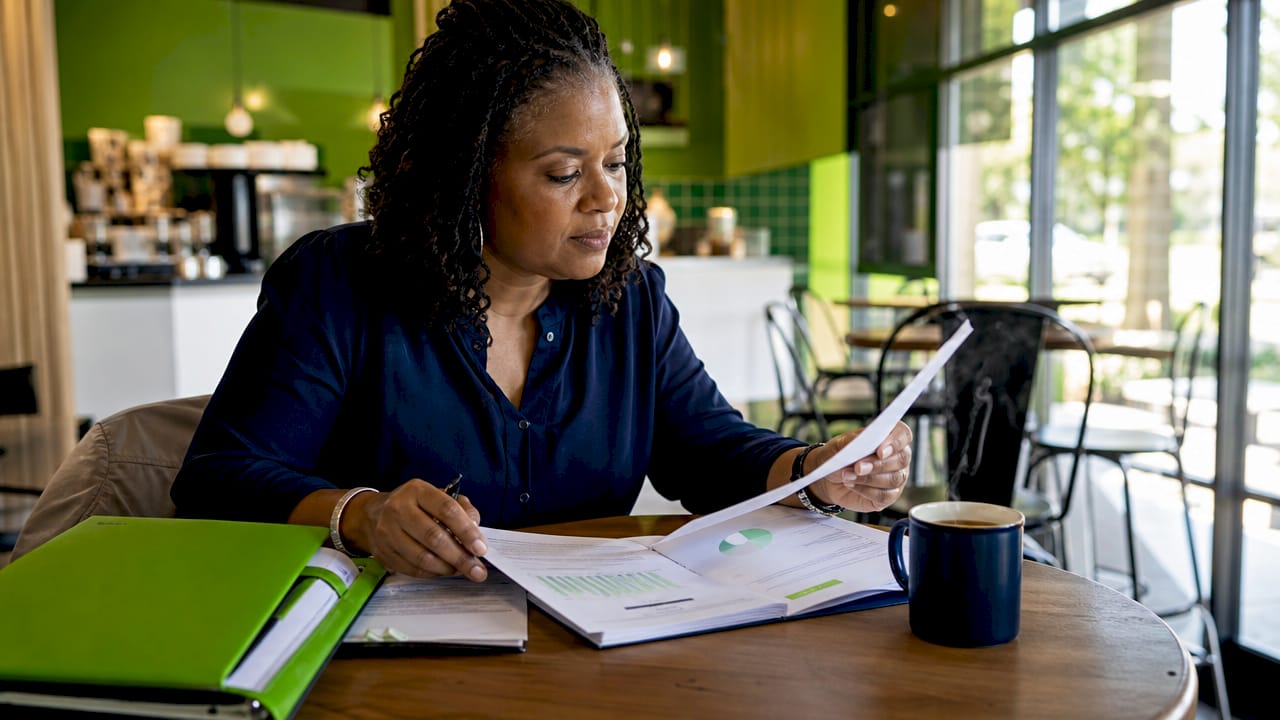 Payroll analyst reviewing payroll registers at desk