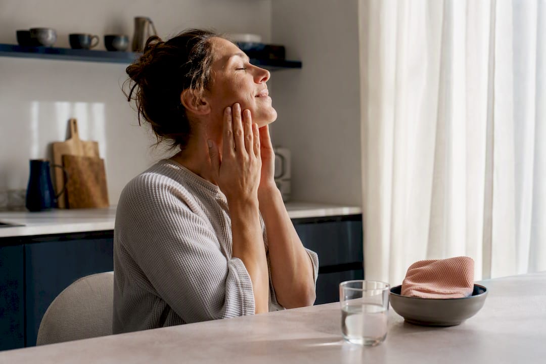 Adult gently massaging jaw for soreness relief