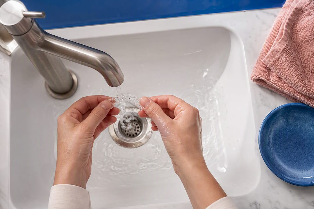 Hands rinsing a clear aligner tray