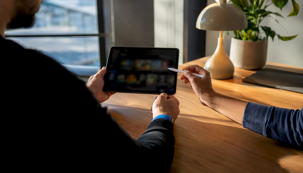 Hands discussing game criteria on tablet