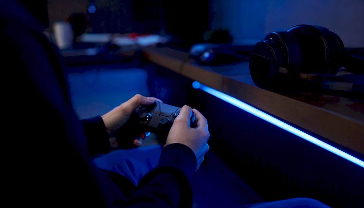 Hands holding controller with gaming headset nearby