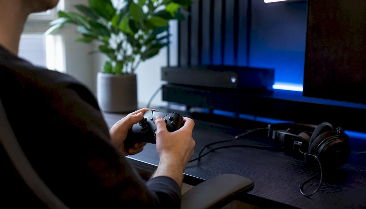 Hands holding gaming controller in PC and Xbox setup