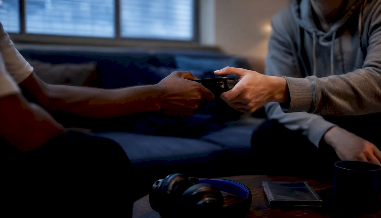 Hands passing game controller during Fortnite