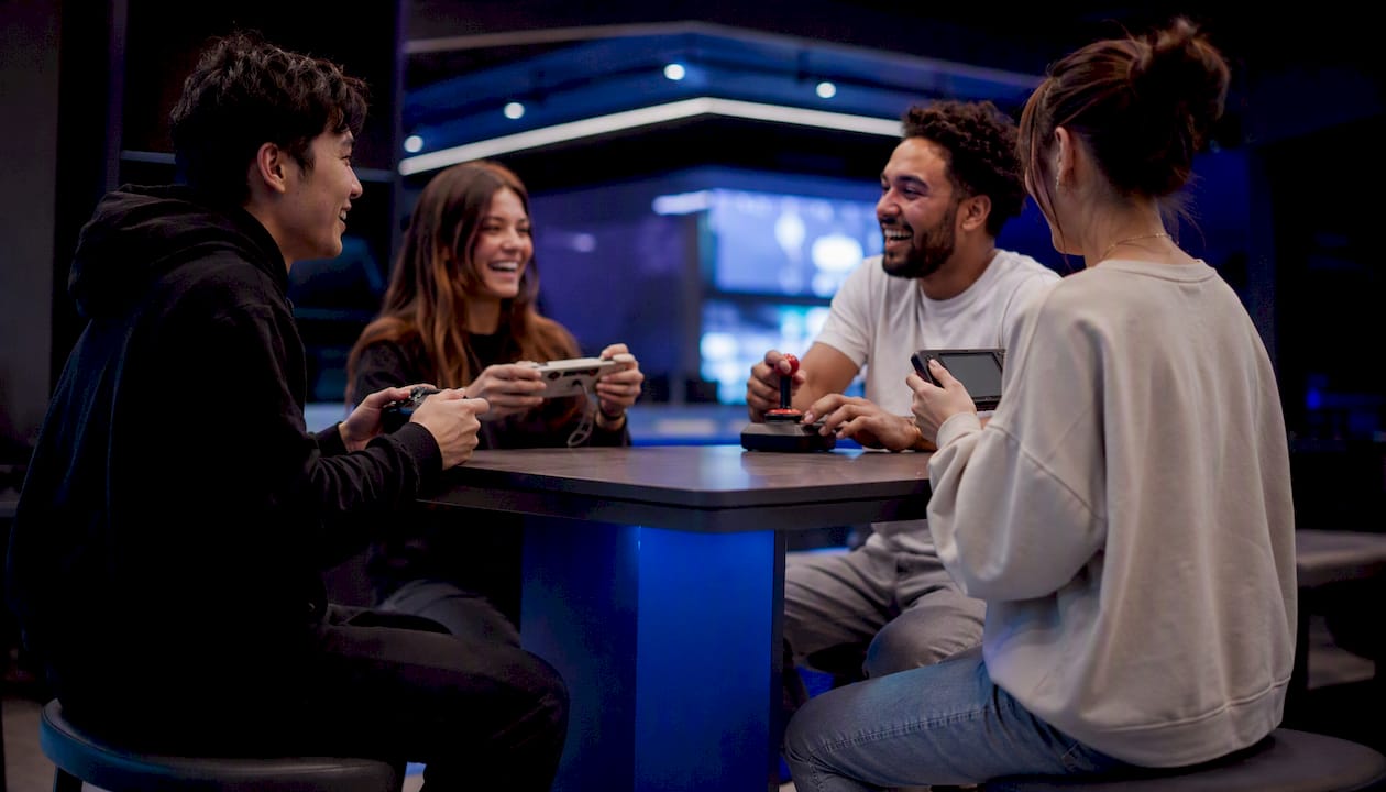 Hands of gamers holding various controllers in lounge