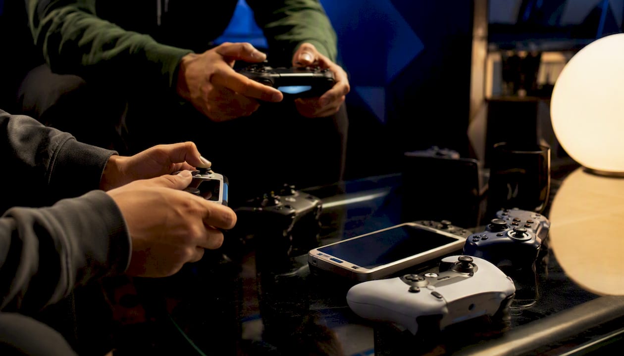 Hands holding various gaming controllers for crossplay