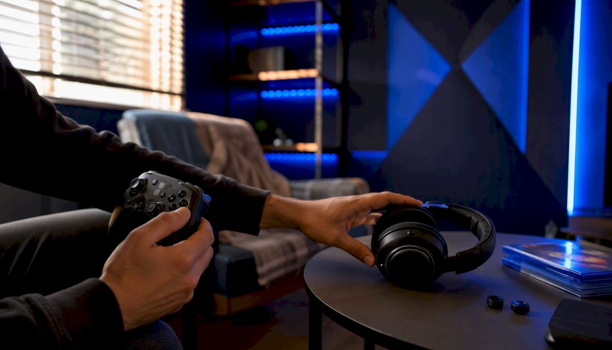 Hands holding game controller in a dark gaming setup