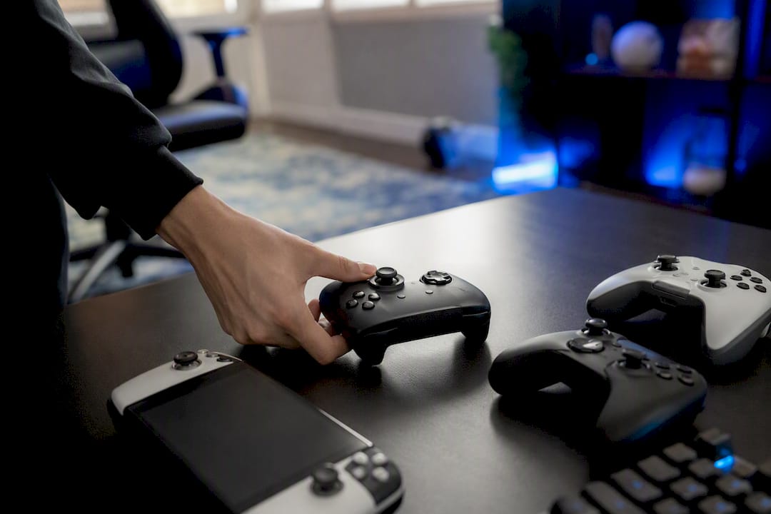 Hand adjusting gaming controller amid varied controllers