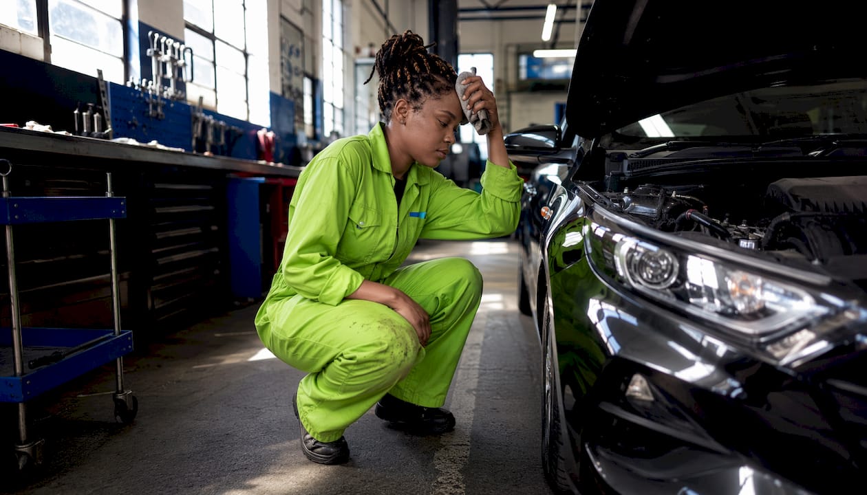 Female mechanic inspecting car engine in garage