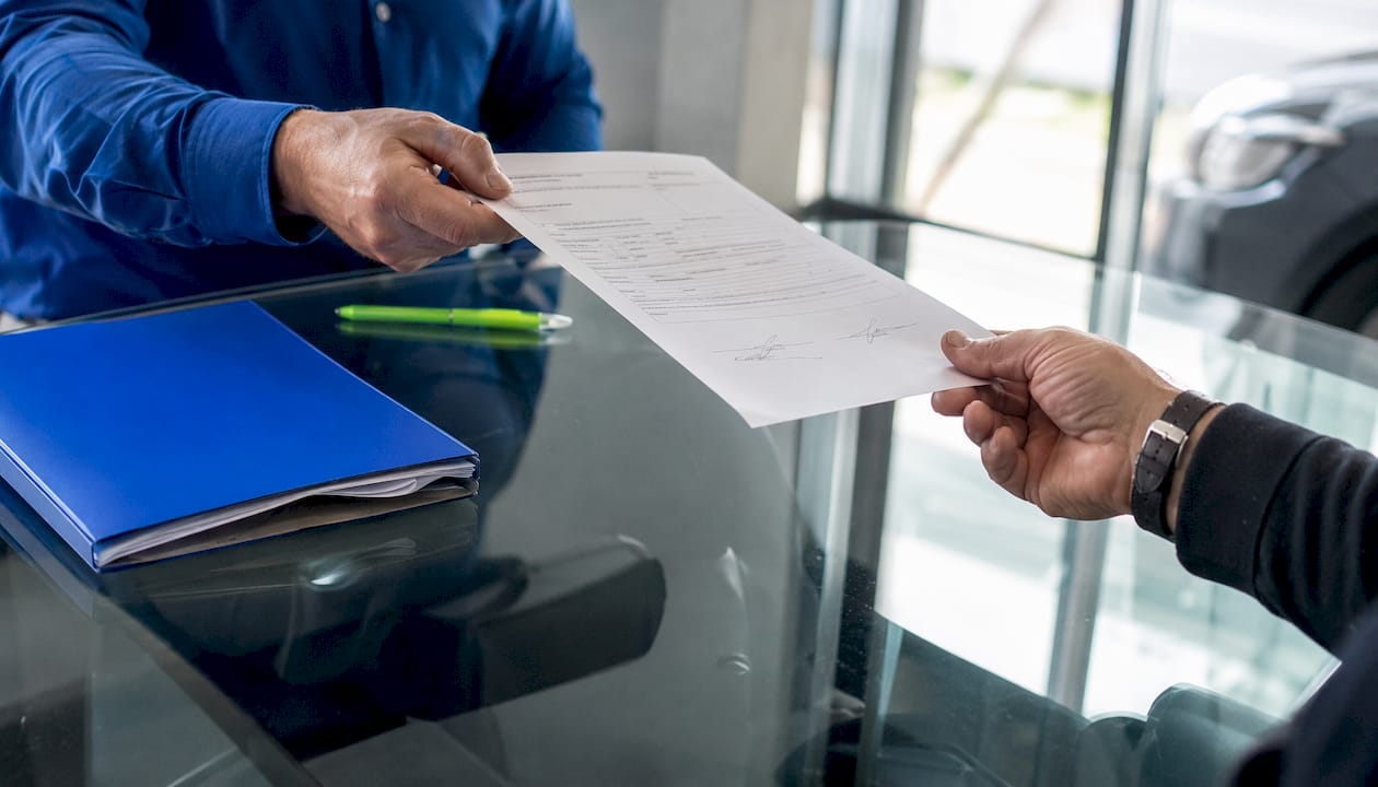 Close-up of hands exchanging bill of sale form