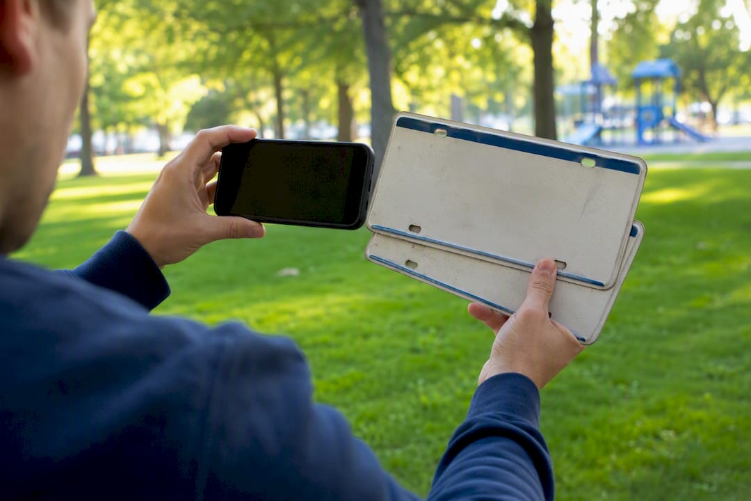 Hands photographing license plates with smartphone