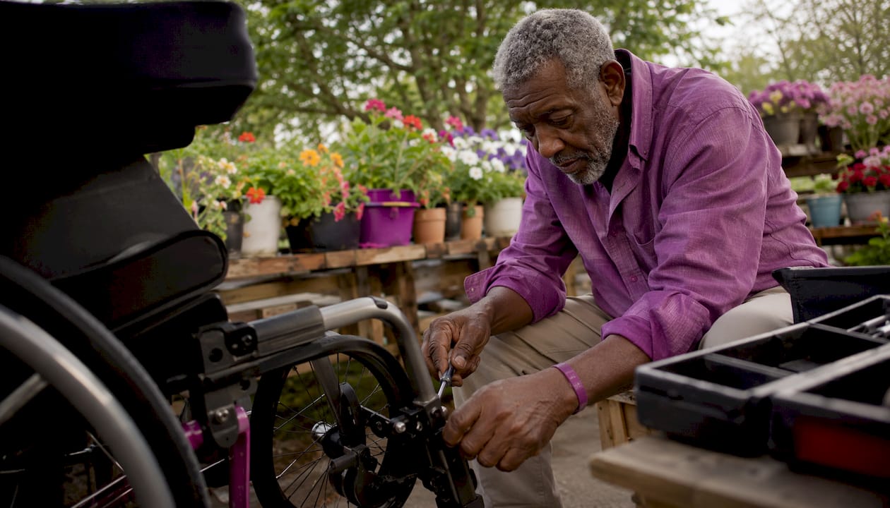 Elderly man adjusting wheelchair brake at bench