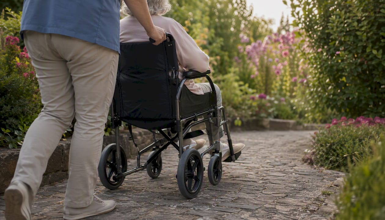 Caregiver pushing transport wheelchair outside