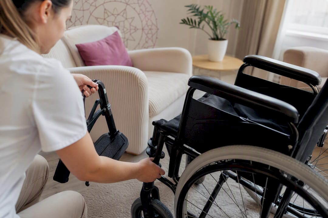 Caregiver preparing wheelchair footrests for transfer