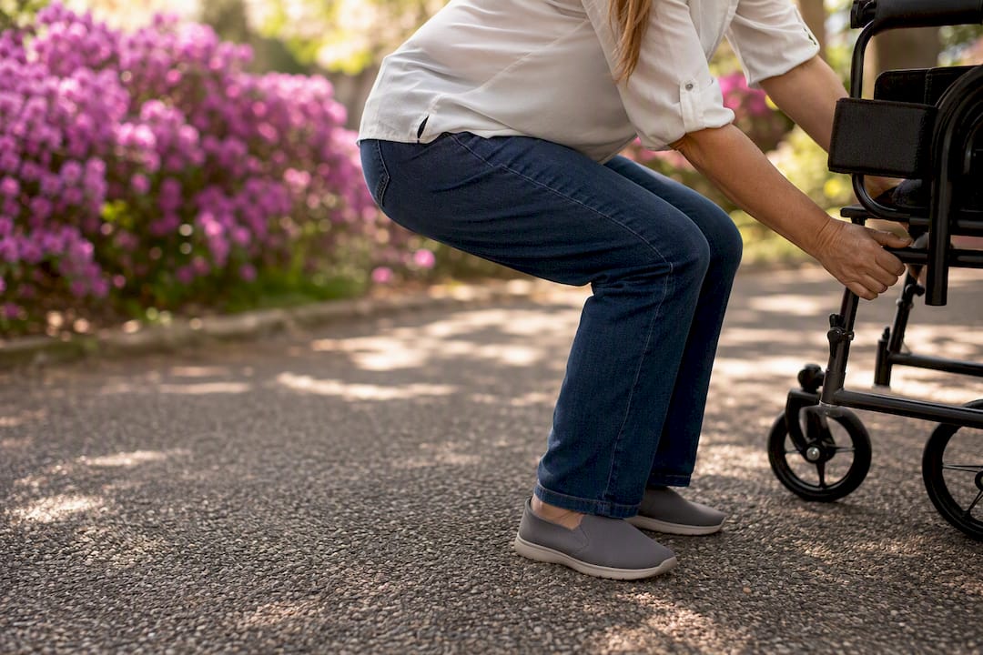 Caregiver bending knees to lift mobility aid frame
