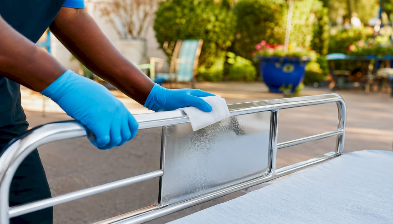 Gloved hands cleaning hospital bed rail