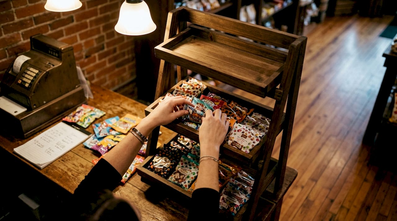 Hands arranging seasonal candy on display rack