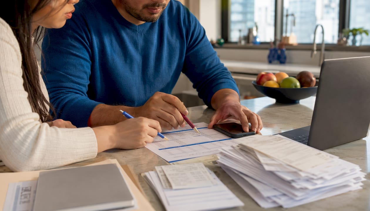Close-up of hands marking operating expenses spreadsheet