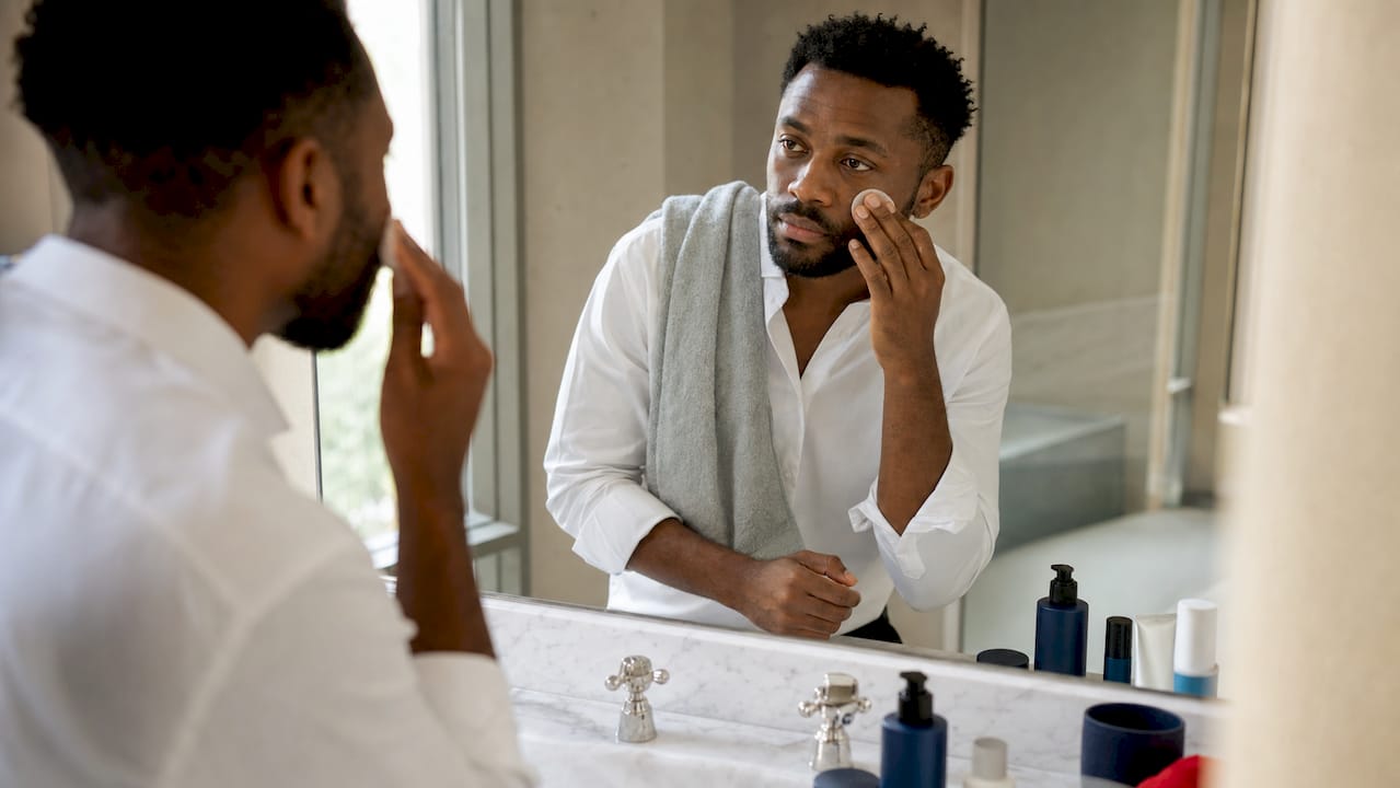 Hands applying tinted SPF on professional man's face