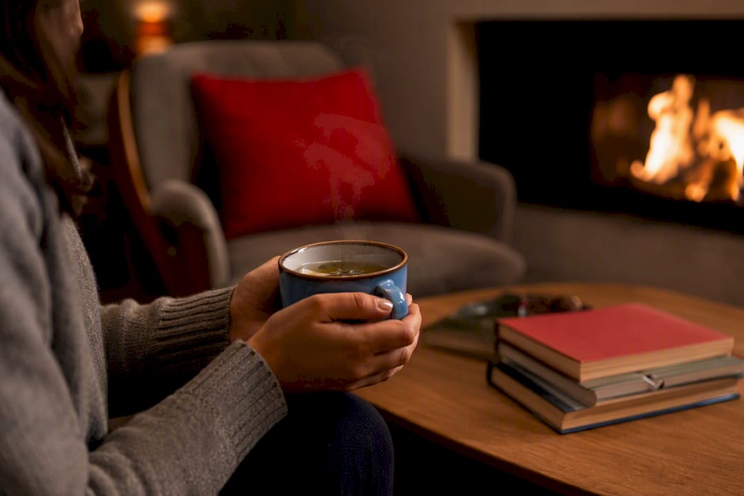 Hands holding herbal tea near candlelight