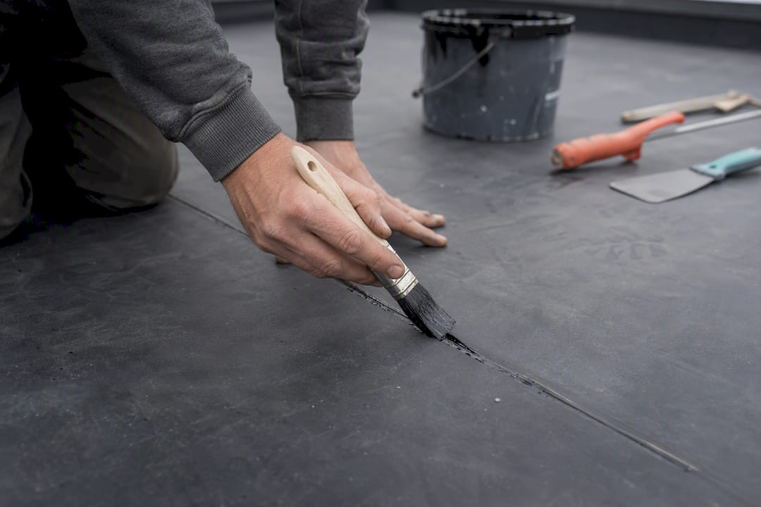 Met zorg worden lijm aangebracht op een scheur in het EPDM dak.