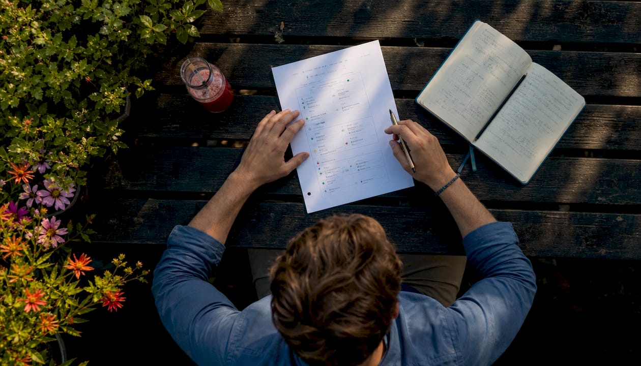 Een paar handen schrijven met pen op papier verschillende formules uit om TikTok-engagement te vergroten.