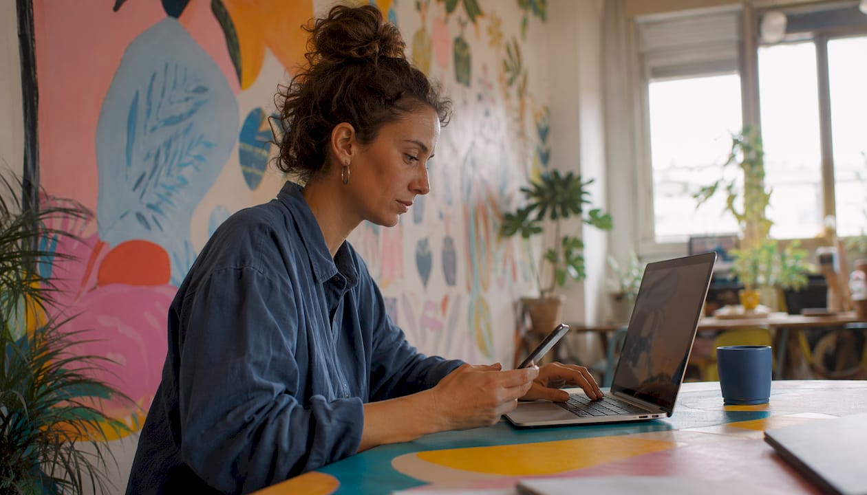 Mensen die op hun laptop en smartphone bezig zijn met het maken van content voor sociale media.