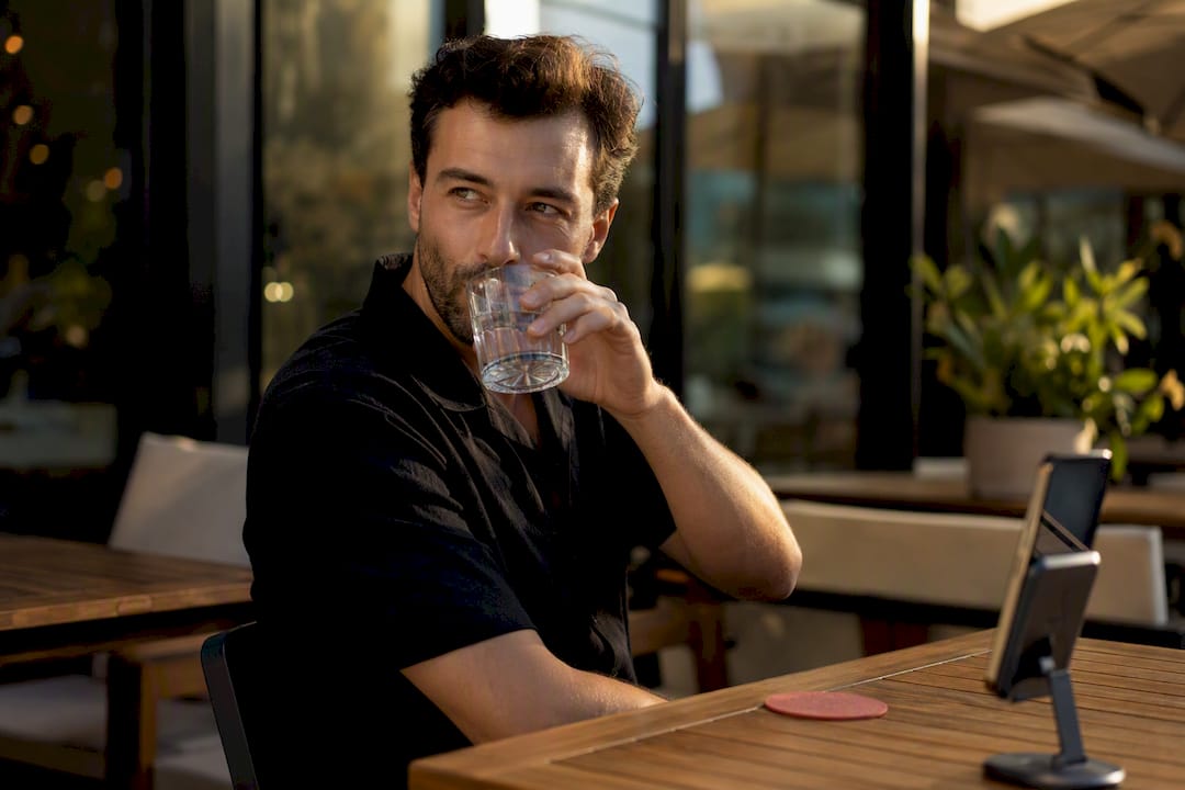 Man taking a sip between portrait frames