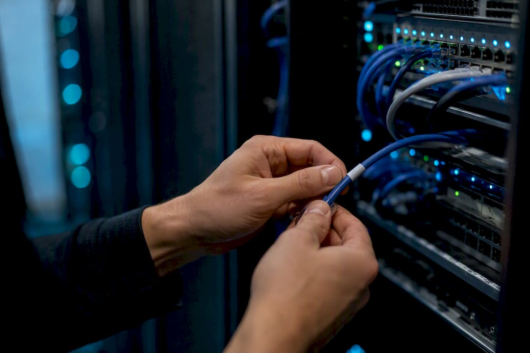 Hands inspecting network cable in server rack