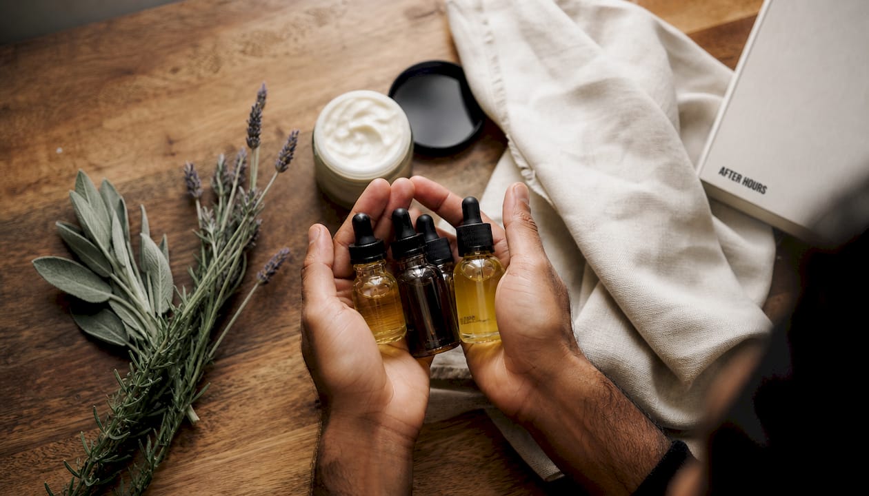Hands holding botanical skincare oil bottles