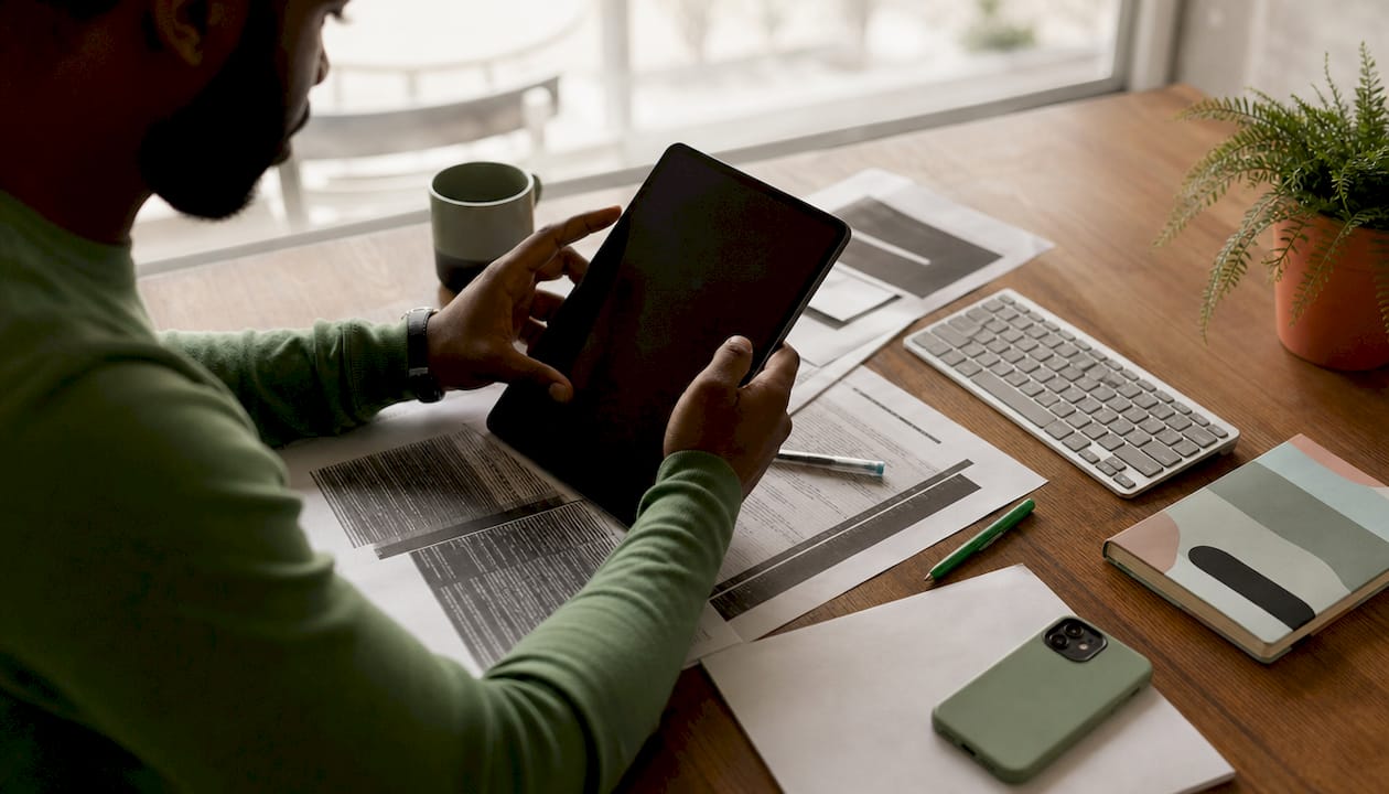 Hands on tablet with technical SEO printouts overhead view