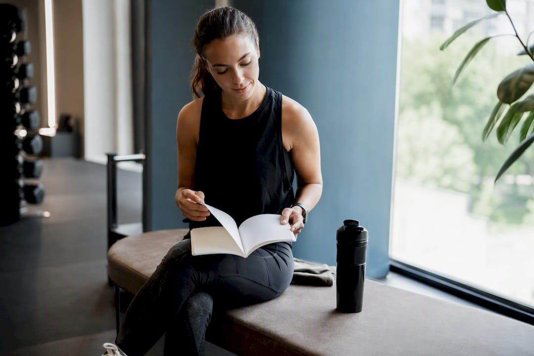 Hands resting on blank fitness journal with gym background