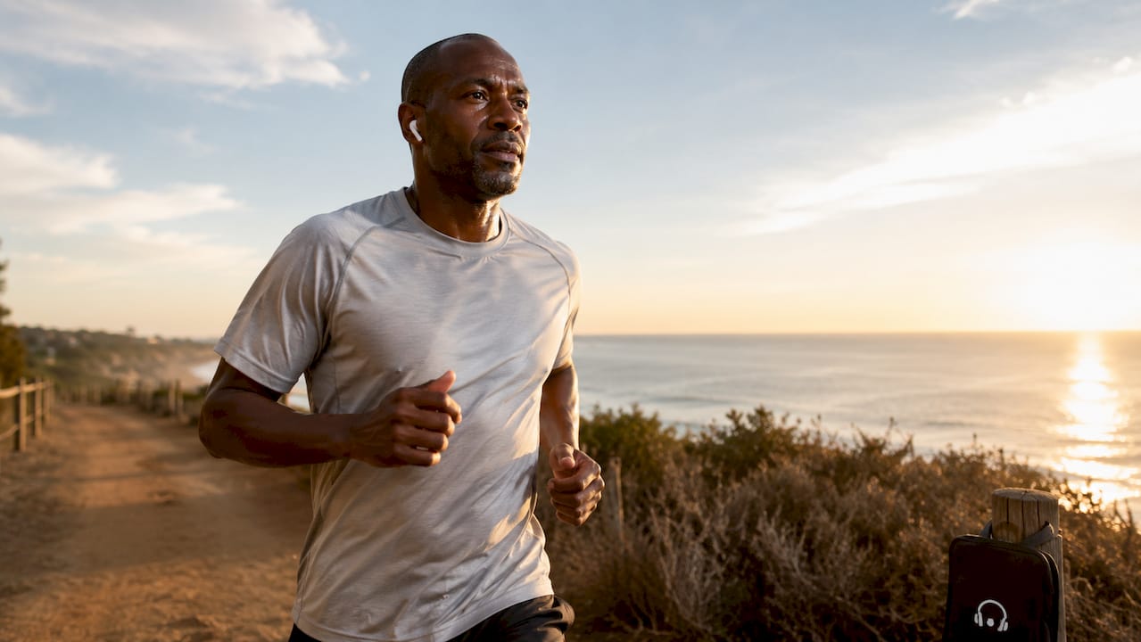 Runner with earbuds jogging outdoors in park