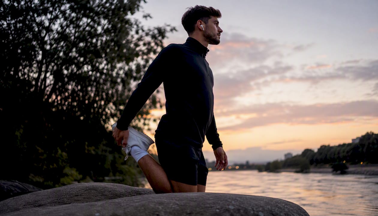 Runner stretching by lake with earbuds