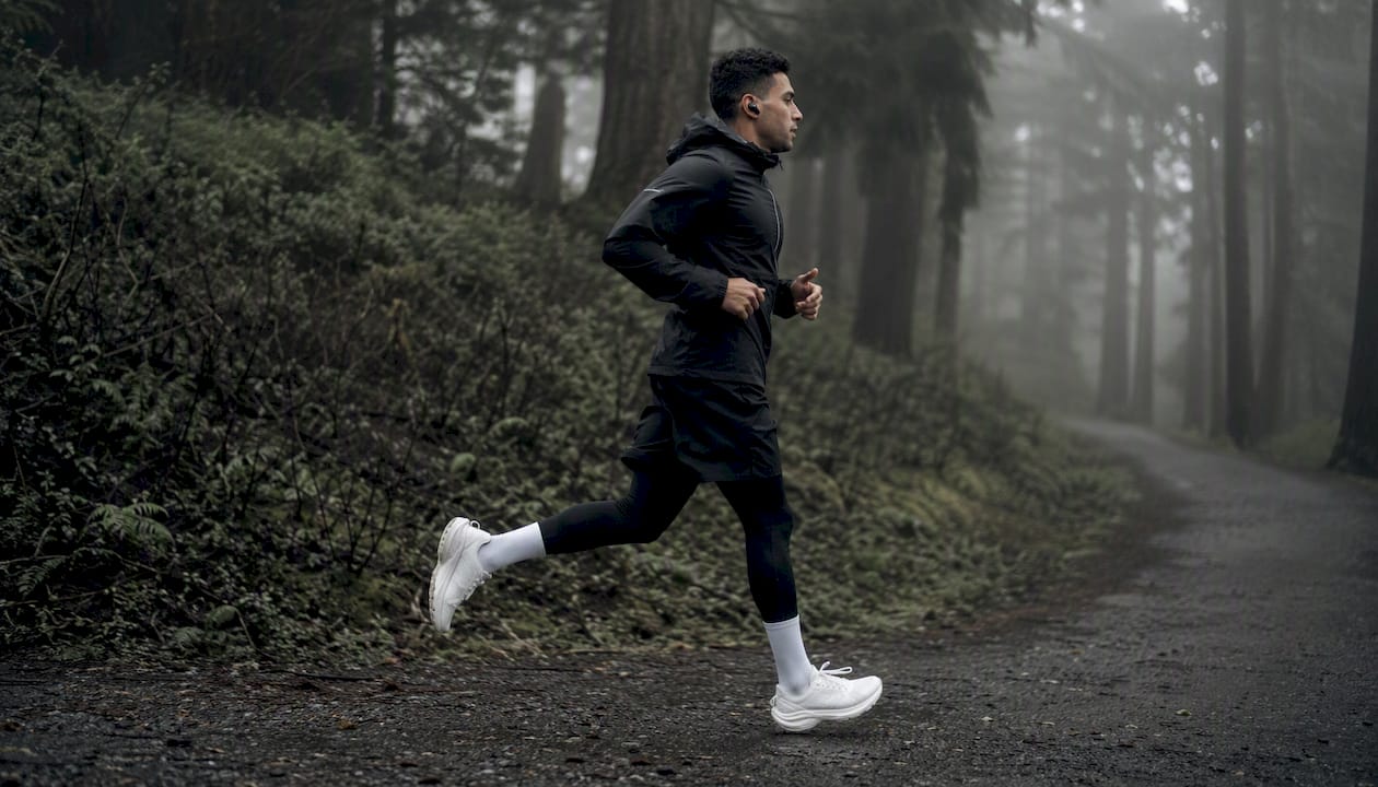 Runner mid-stride with earphones on trail