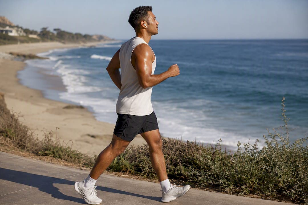 Person walking outdoors with earbuds mid-stride