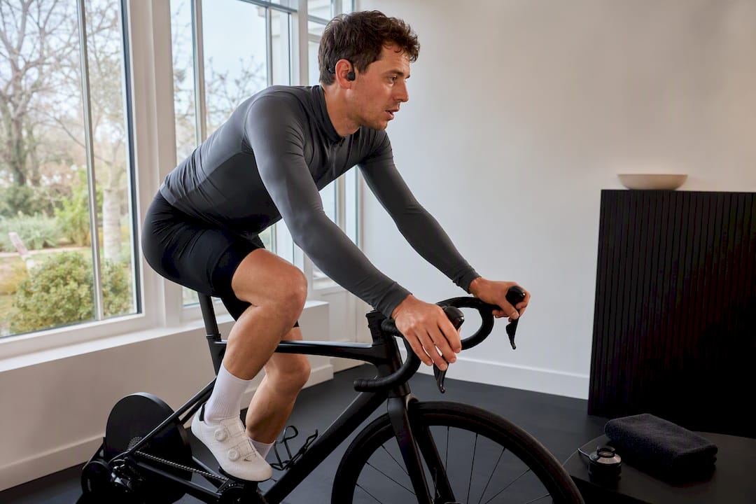 Cyclist wearing open-ear headphones while training