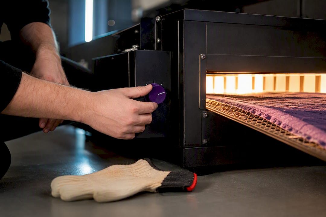 Technician controlling heat on garment curing tunnel