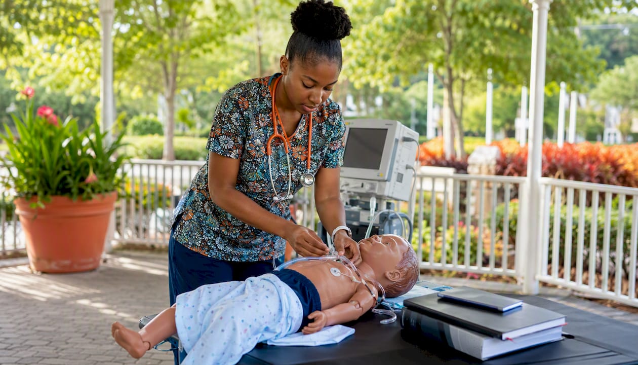 Nurse adjusting pediatric medical device in training room