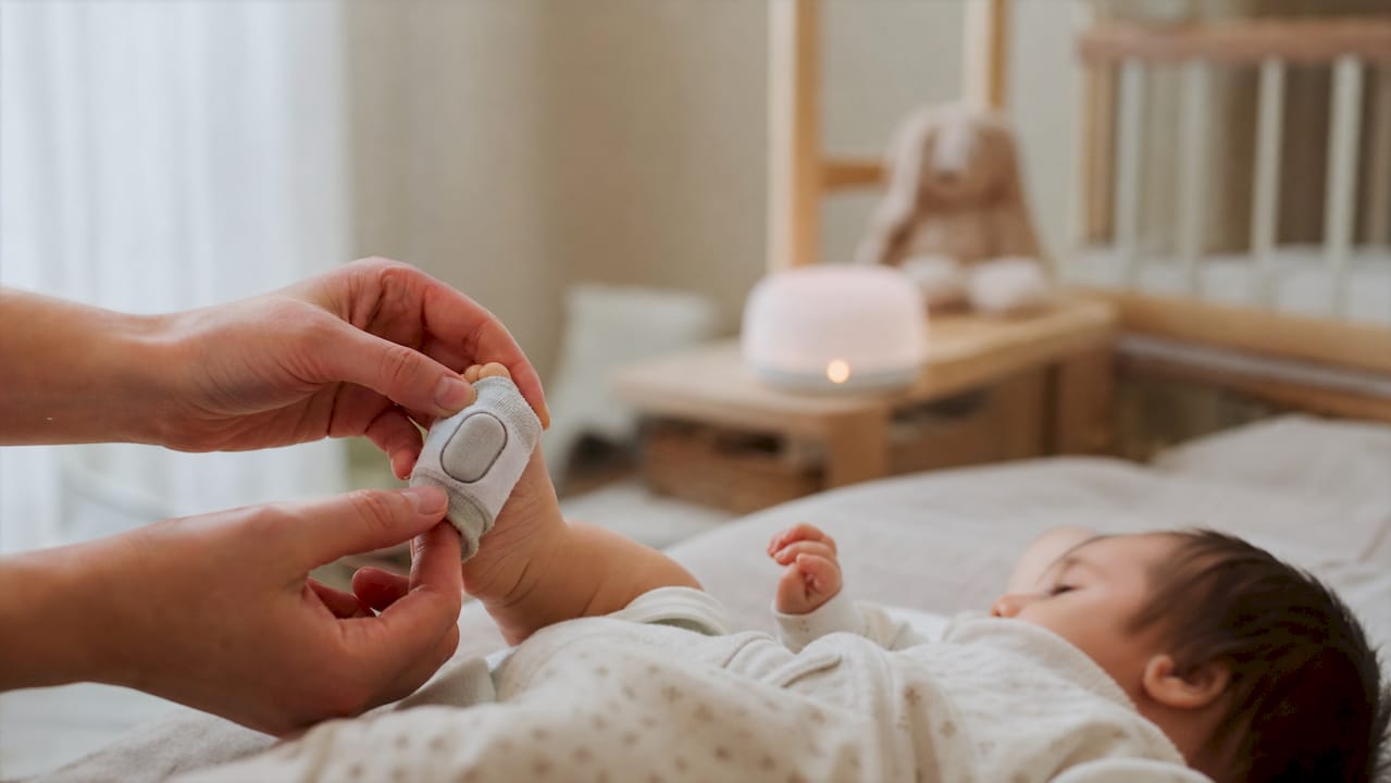 Parent adjusting infant pulse oximeter sock sensor