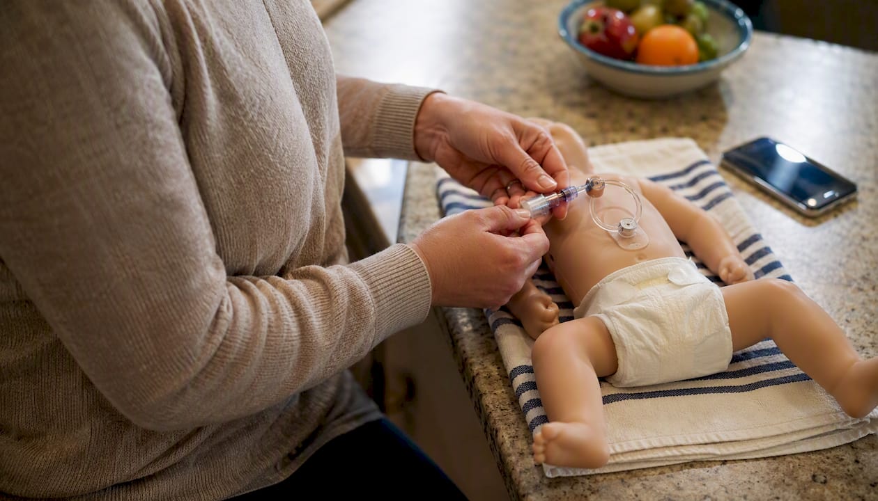 Parent practicing G-tube care on training model