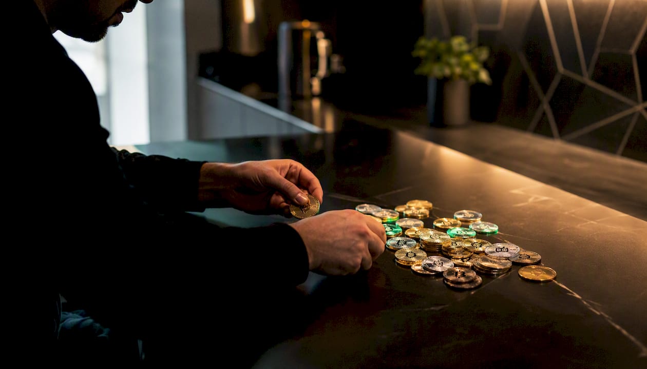 Hands organizing cryptocurrency coins on wood