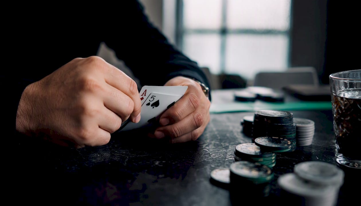 Hands holding playing cards over dark table