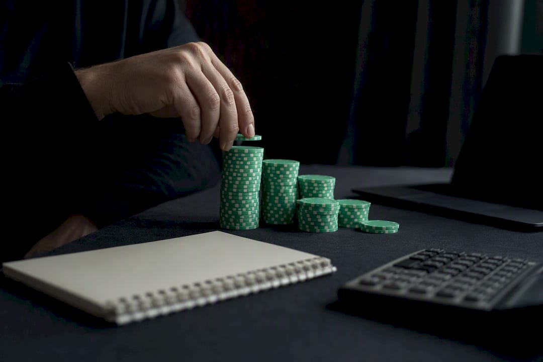 Hand placing gambling chips near calculator