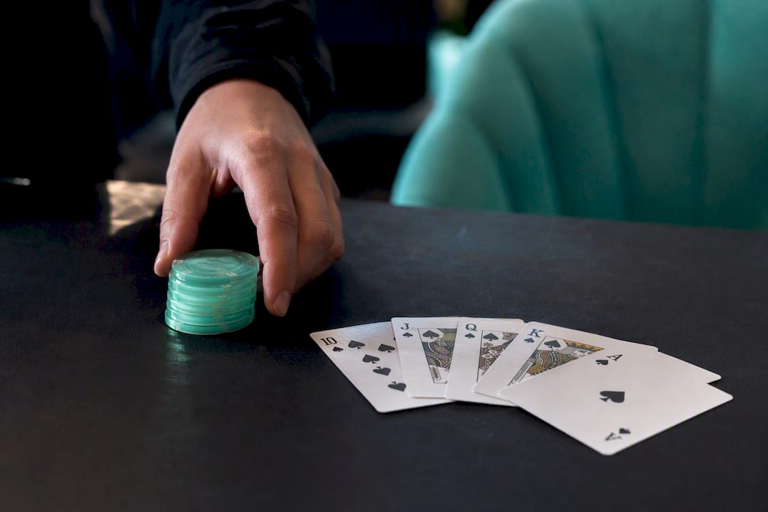 Hand placing chips near blackjack cards on table