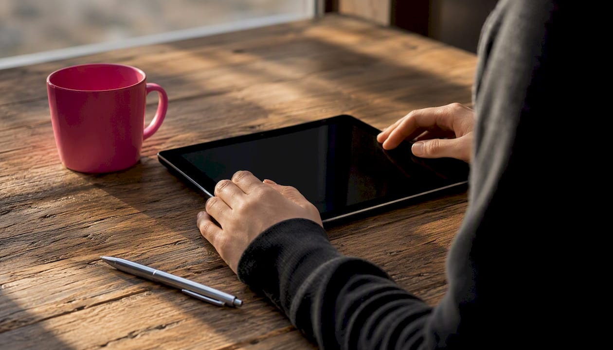 Hands holding tablet off, preparing to check report