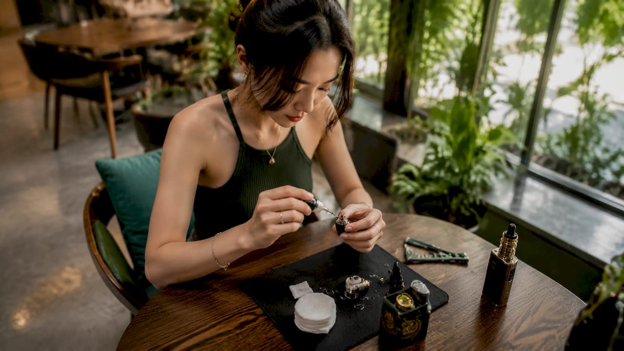 Woman priming vape coil at desk